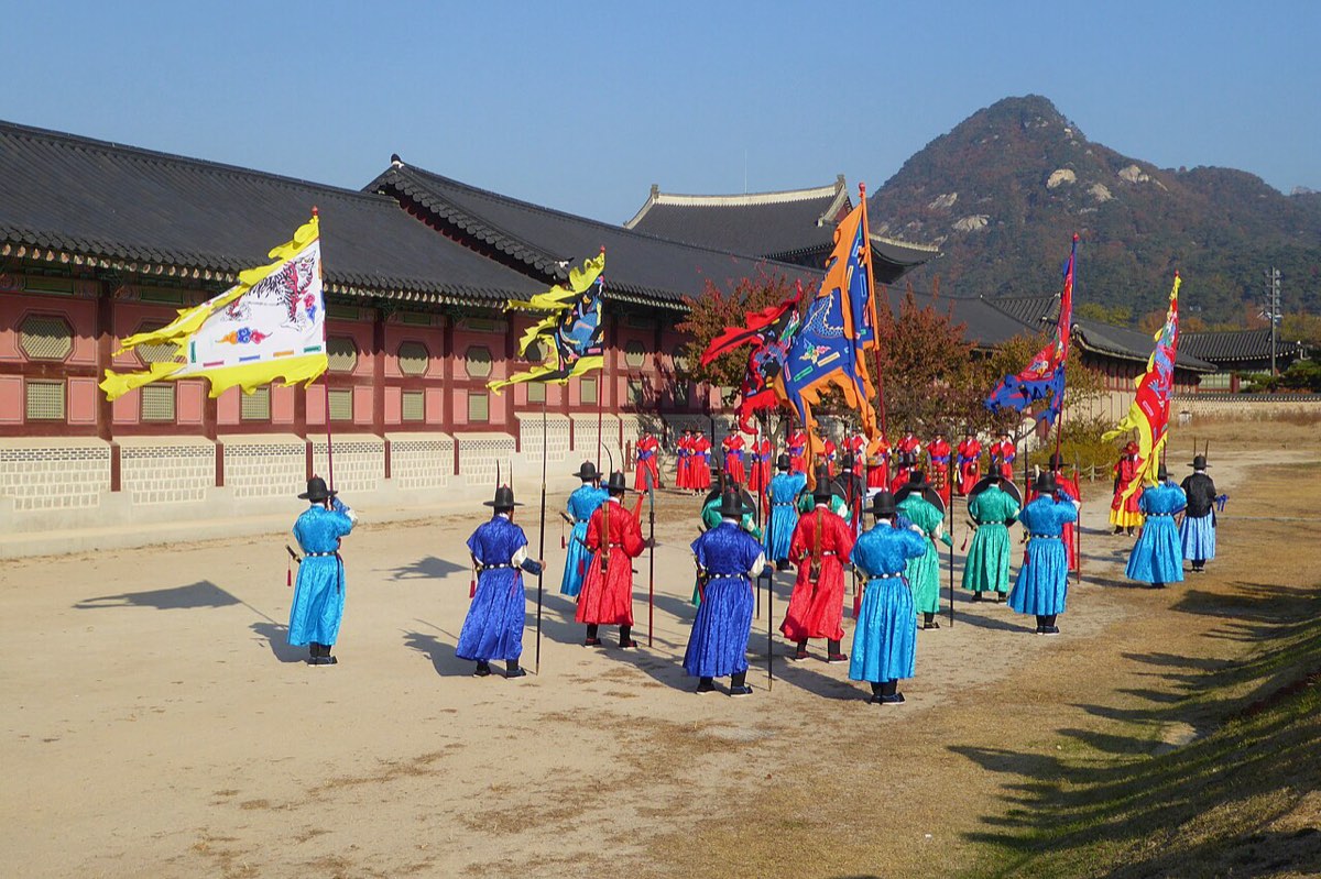 Royal gate guards in Joseon-style uniforms and banners during the changing ceremony at Gyeongbokgung Palace.