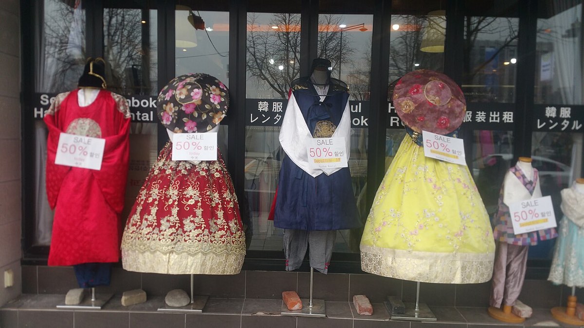 Rental hanbok with lace, glitter prints and bright satin displayed in a shop window near Gyeongbokgung.
