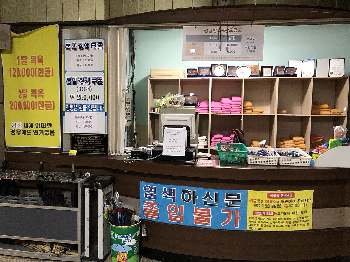The front counter of a Korean jjimjilbang, with shelves of folded towels and uniforms for arriving guests.