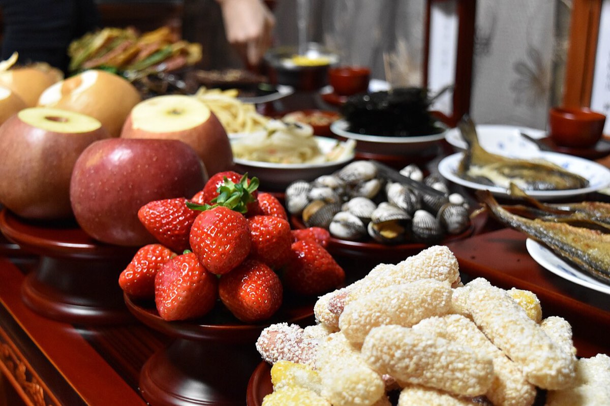 A charye-sang ancestral rite table laid with apples, strawberries, rice cakes, fish and other offerings.