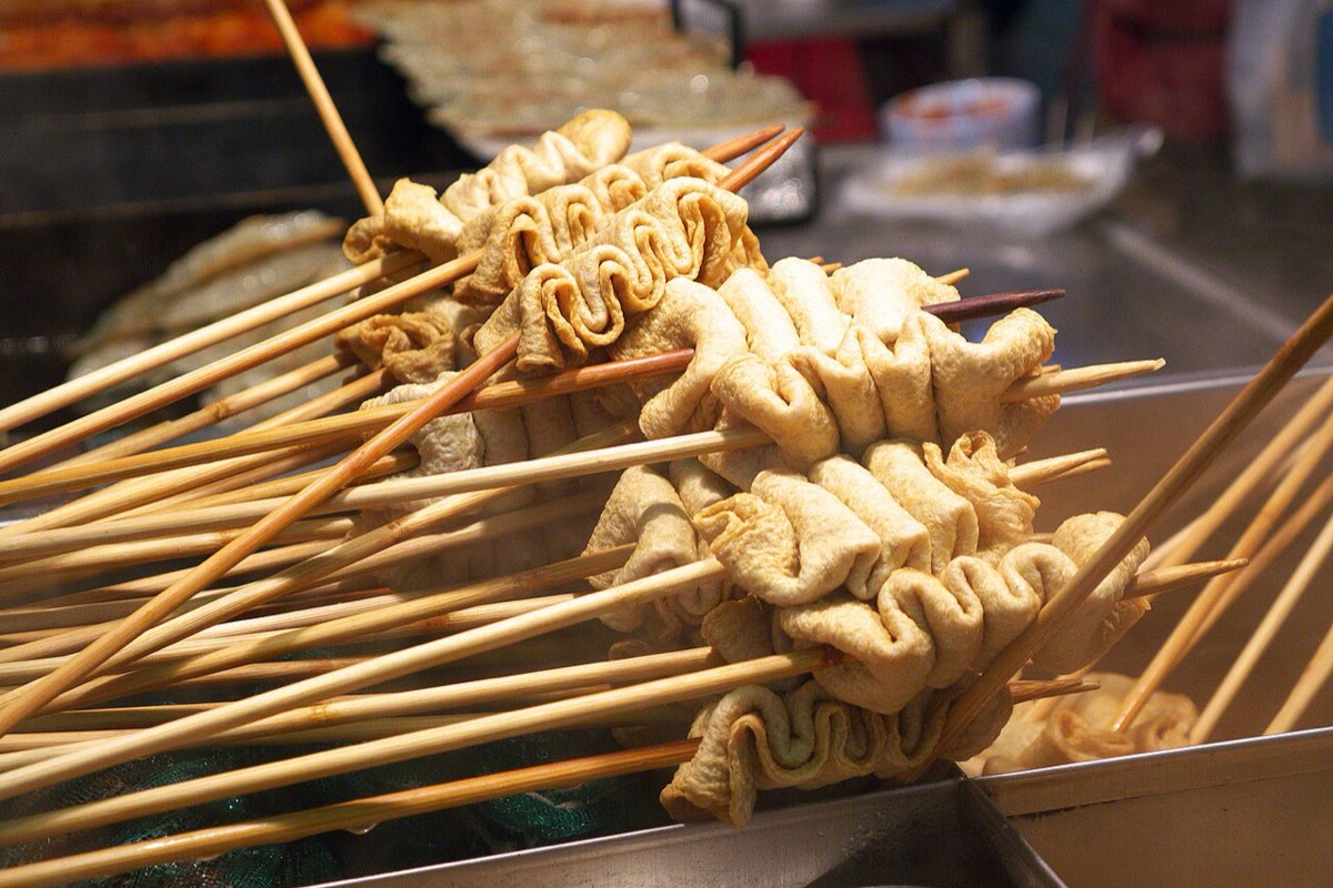 Skewers of eomuk, Korean fish cake, simmering in broth at a street food stall.