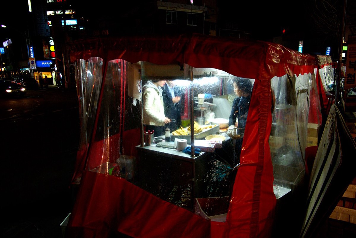 A pojangmacha, a tented street food stall, lit up from inside at night in Seoul.