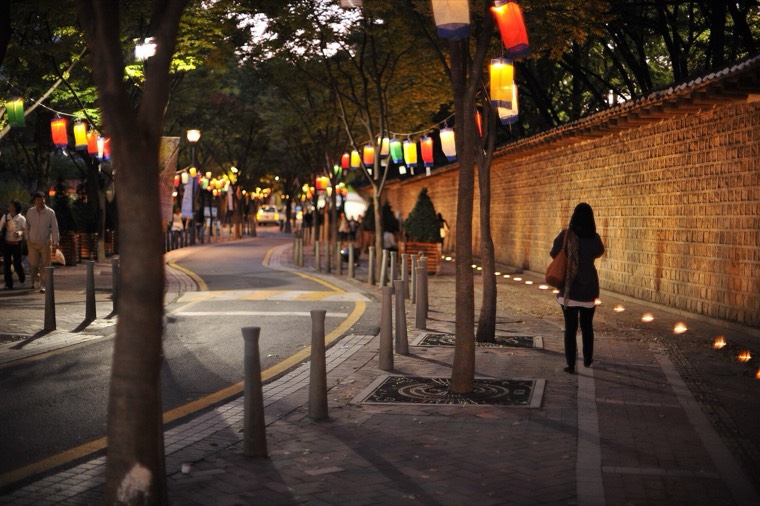 Deoksugung's stone-wall road at night, lit by street lamps