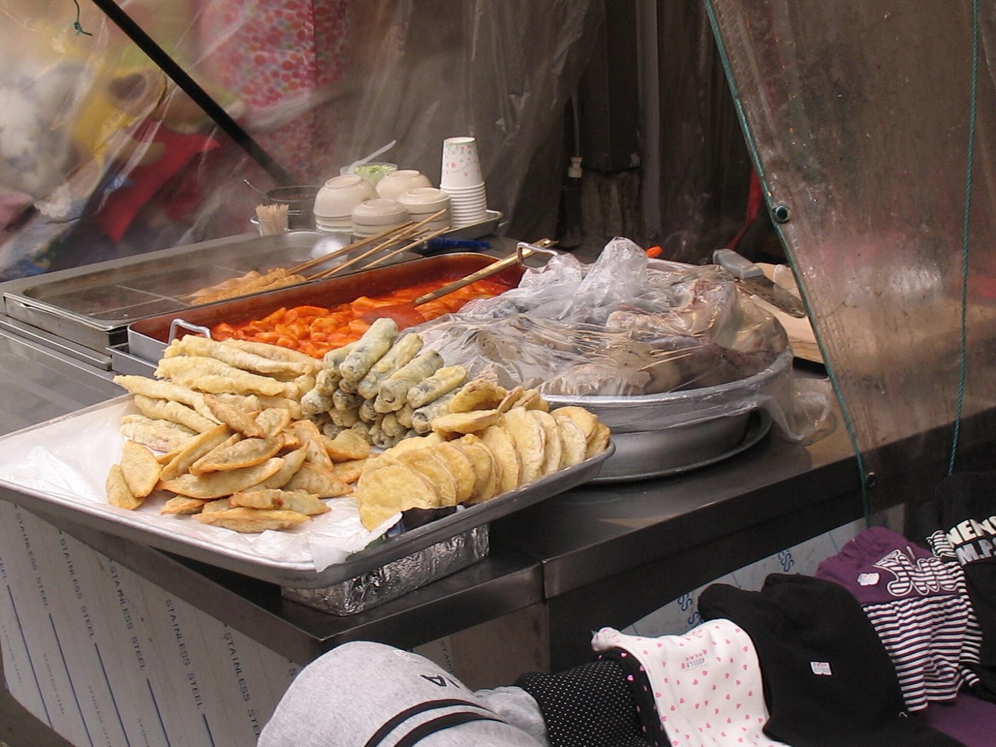 A bunsik street-food stall with fried snacks under the counter lights