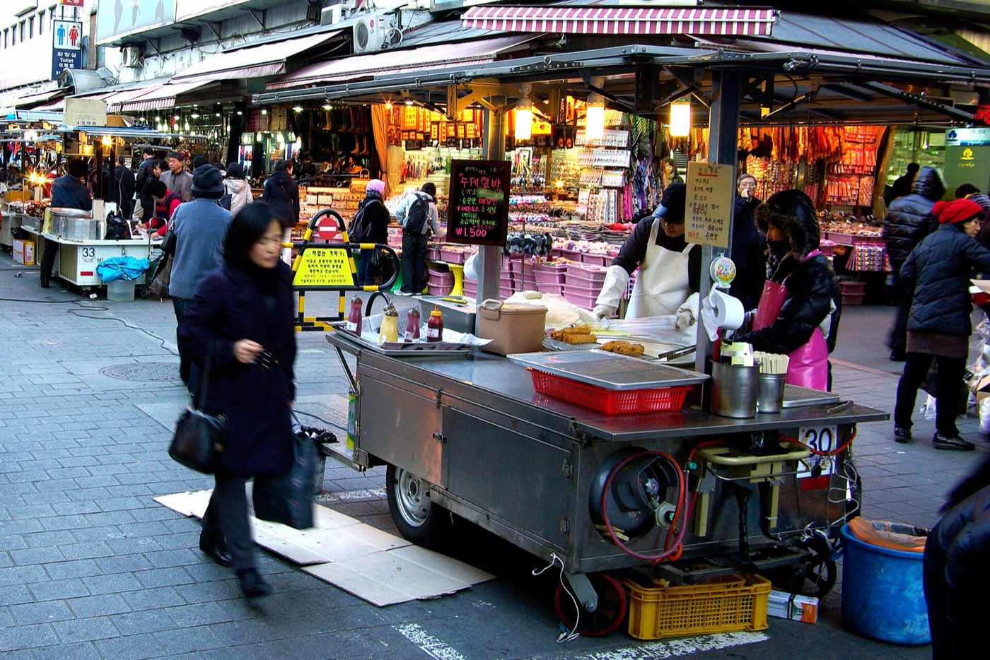 A street-food cart set up on a busy Seoul shopping street